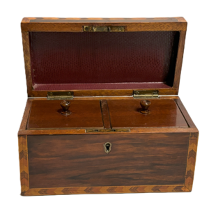 A vintage English tea caddy, made of wood, featuring two compartments for storing tea.