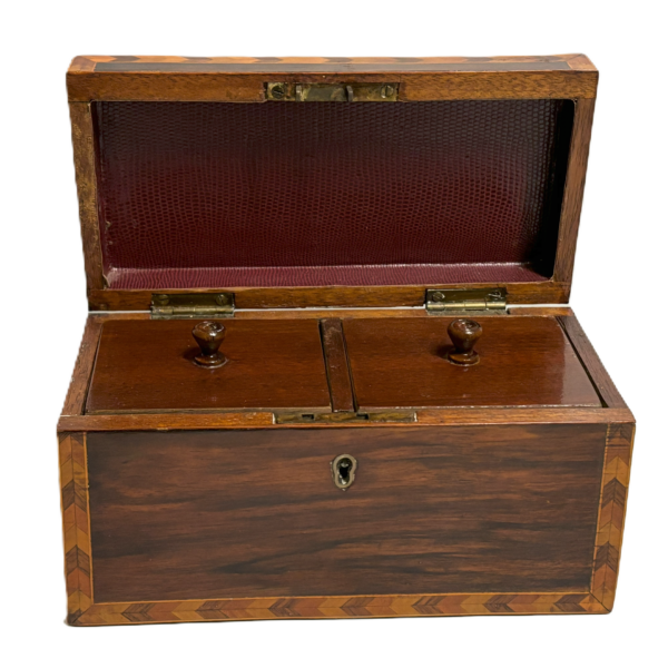 A vintage English tea caddy, made of wood, featuring two compartments for storing tea.